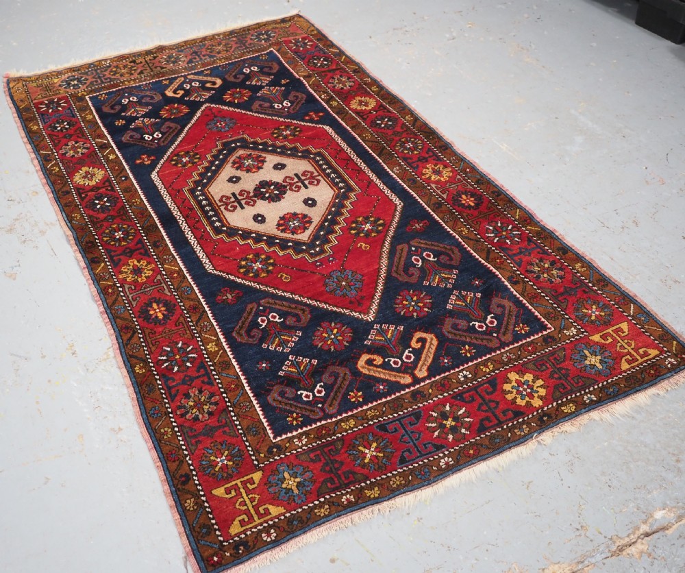 An antique hand-knotted Turkish Yahyali wool rug featuring a central geometric medallion design in red, cream, and navy blue with ornate floral borders. View II