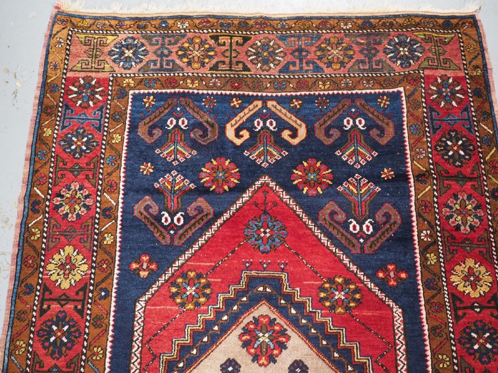 An antique hand-knotted Turkish Yahyali wool rug featuring a central geometric medallion design in red, cream, and navy blue with ornate floral borders. View III
