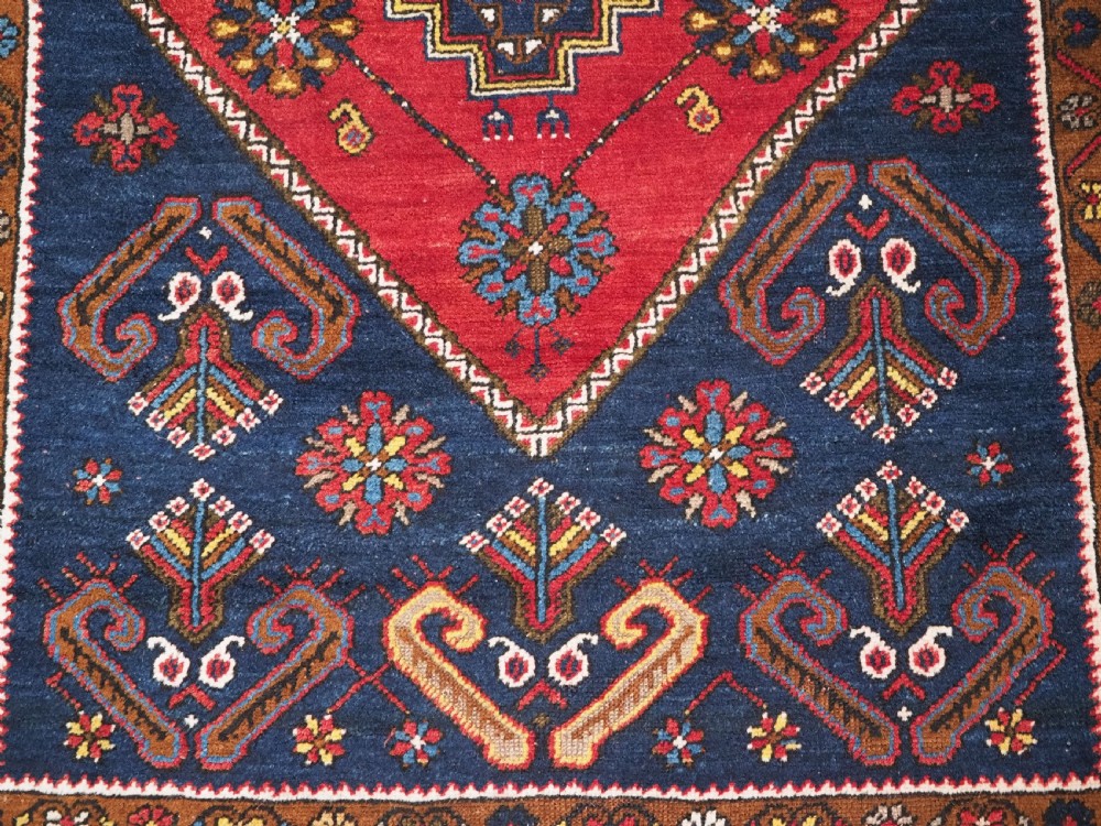 An antique hand-knotted Turkish Yahyali wool rug featuring a central geometric medallion design in red, cream, and navy blue with ornate floral borders. View X