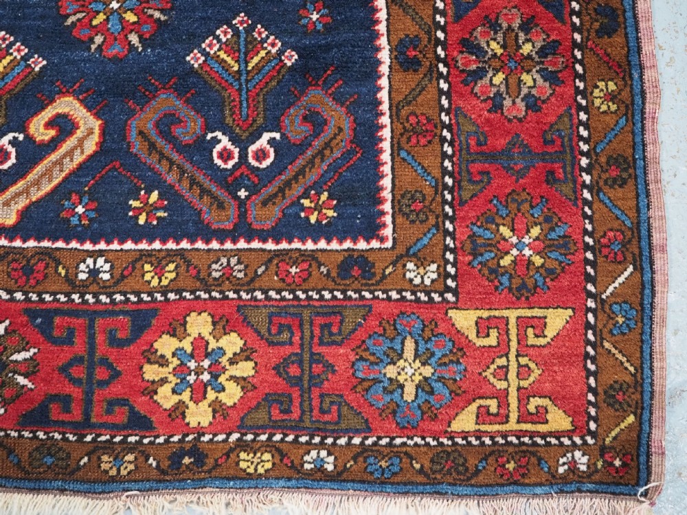 An antique hand-knotted Turkish Yahyali wool rug featuring a central geometric medallion design in red, cream, and navy blue with ornate floral borders. View XI