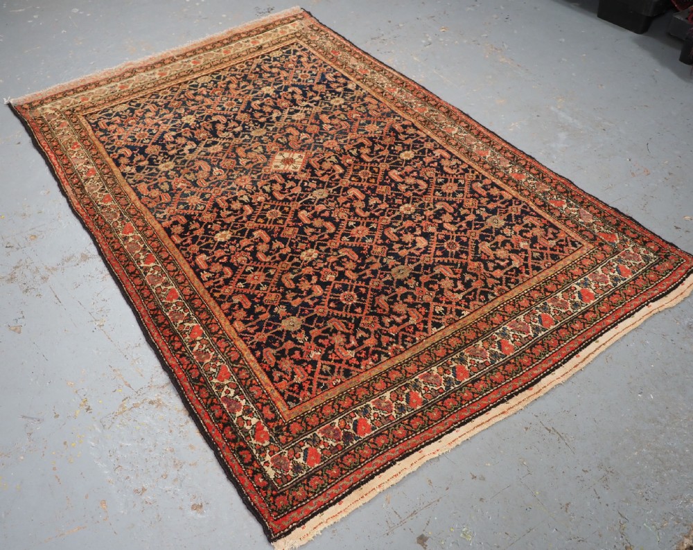 An antique Persian Malayer hand-knotted wool rug featuring an intricate all-over Herati lattice pattern on a dark navy blue field surrounded by multi-layered terracotta floral borders. View II