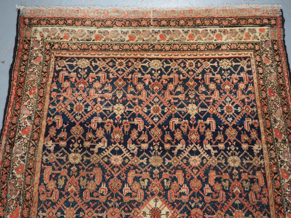 An antique Persian Malayer hand-knotted wool rug featuring an intricate all-over Herati lattice pattern on a dark navy blue field surrounded by multi-layered terracotta floral borders. View III