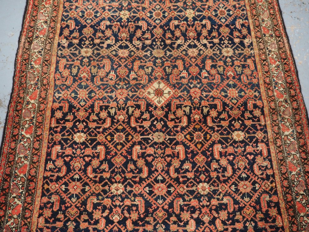 An antique Persian Malayer hand-knotted wool rug featuring an intricate all-over Herati lattice pattern on a dark navy blue field surrounded by multi-layered terracotta floral borders. View IV