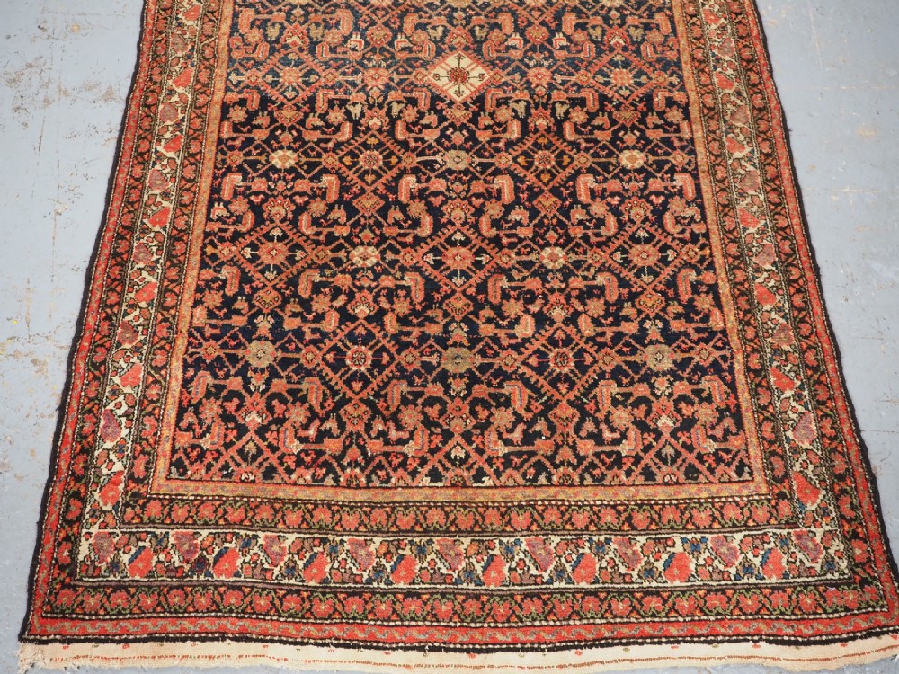An antique Persian Malayer hand-knotted wool rug featuring an intricate all-over Herati lattice pattern on a dark navy blue field surrounded by multi-layered terracotta floral borders. View V
