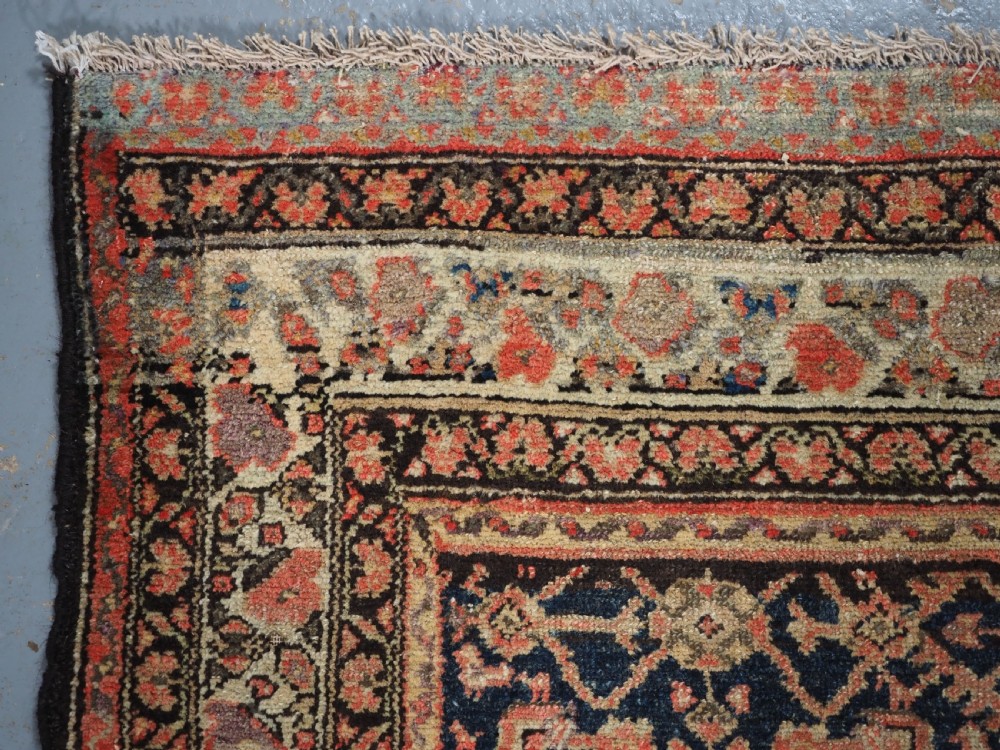 An antique Persian Malayer hand-knotted wool rug featuring an intricate all-over Herati lattice pattern on a dark navy blue field surrounded by multi-layered terracotta floral borders. View VI