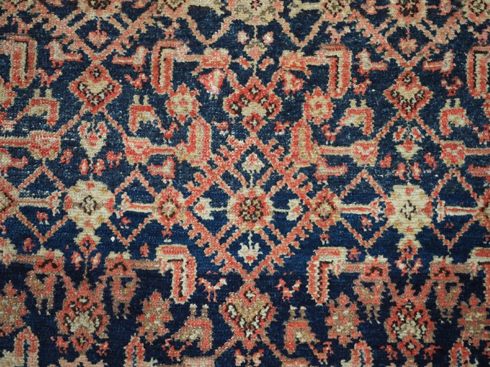 An antique Persian Malayer hand-knotted wool rug featuring an intricate all-over Herati lattice pattern on a dark navy blue field surrounded by multi-layered terracotta floral borders. View VIII