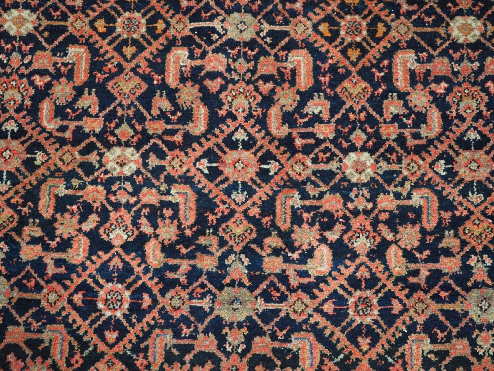 An antique Persian Malayer hand-knotted wool rug featuring an intricate all-over Herati lattice pattern on a dark navy blue field surrounded by multi-layered terracotta floral borders. View X