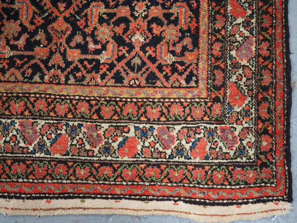 An antique Persian Malayer hand-knotted wool rug featuring an intricate all-over Herati lattice pattern on a dark navy blue field surrounded by multi-layered terracotta floral borders. View XII