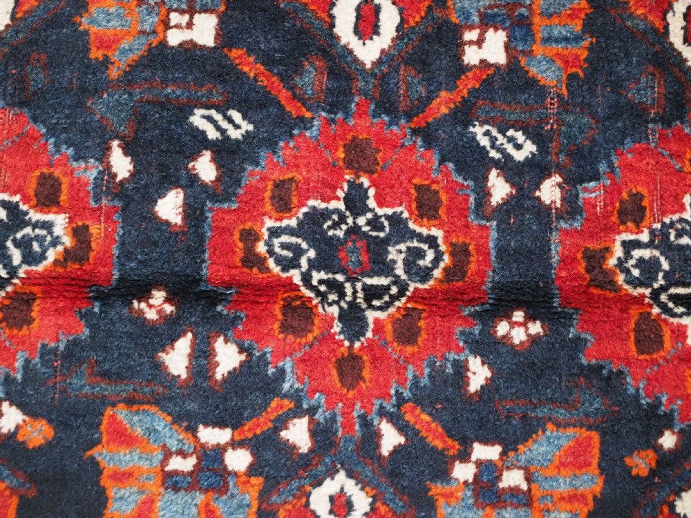 An antique hand-knotted Persian Shiraz wool rug featuring geometric tribal medallions in red, dark blue, and ivory. View VIII
