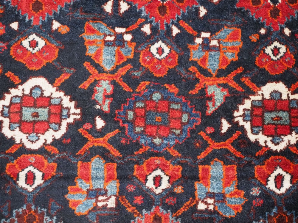 An antique hand-knotted Persian Shiraz wool rug featuring geometric tribal medallions in red, dark blue, and ivory. View IX