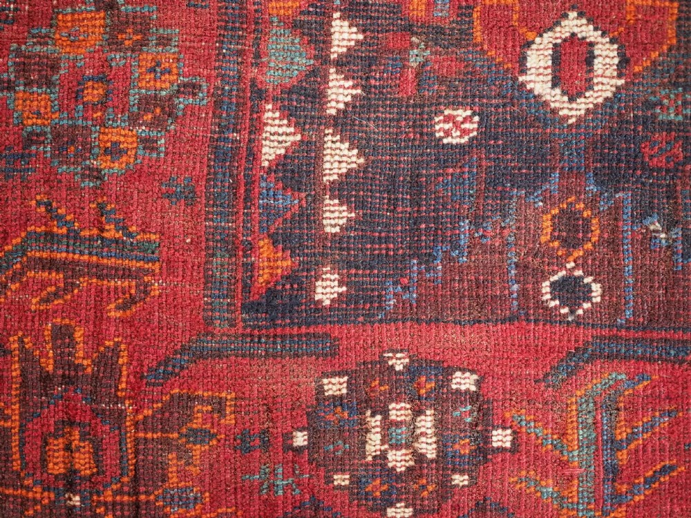 An antique hand-knotted Persian Shiraz wool rug featuring geometric tribal medallions in red, dark blue, and ivory. View XI