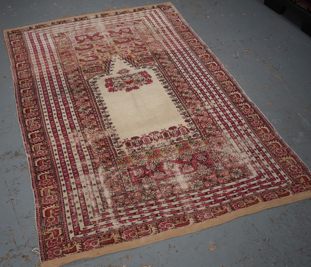 An antique Turkish Ghiordes prayer rug featuring a cream central niche framed by multi-banded red and burgundy patterned borders. View II