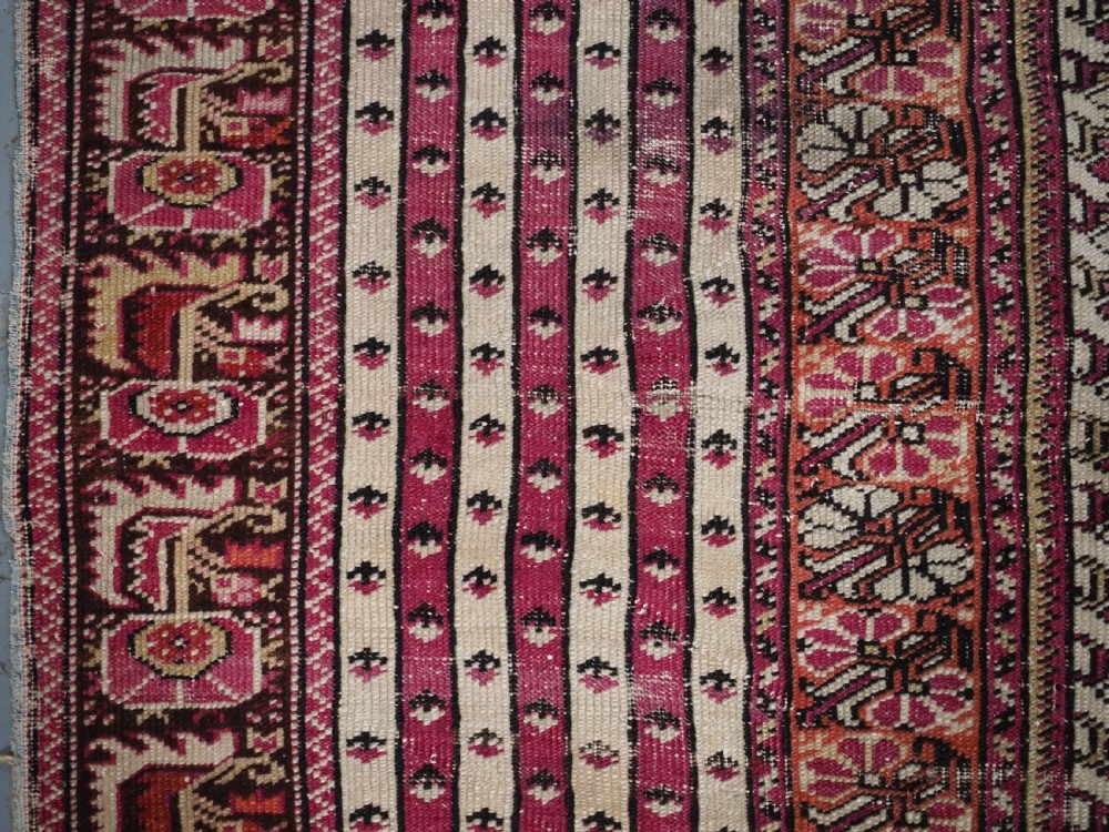 An antique Turkish Ghiordes prayer rug featuring a cream central niche framed by multi-banded red and burgundy patterned borders. View VII