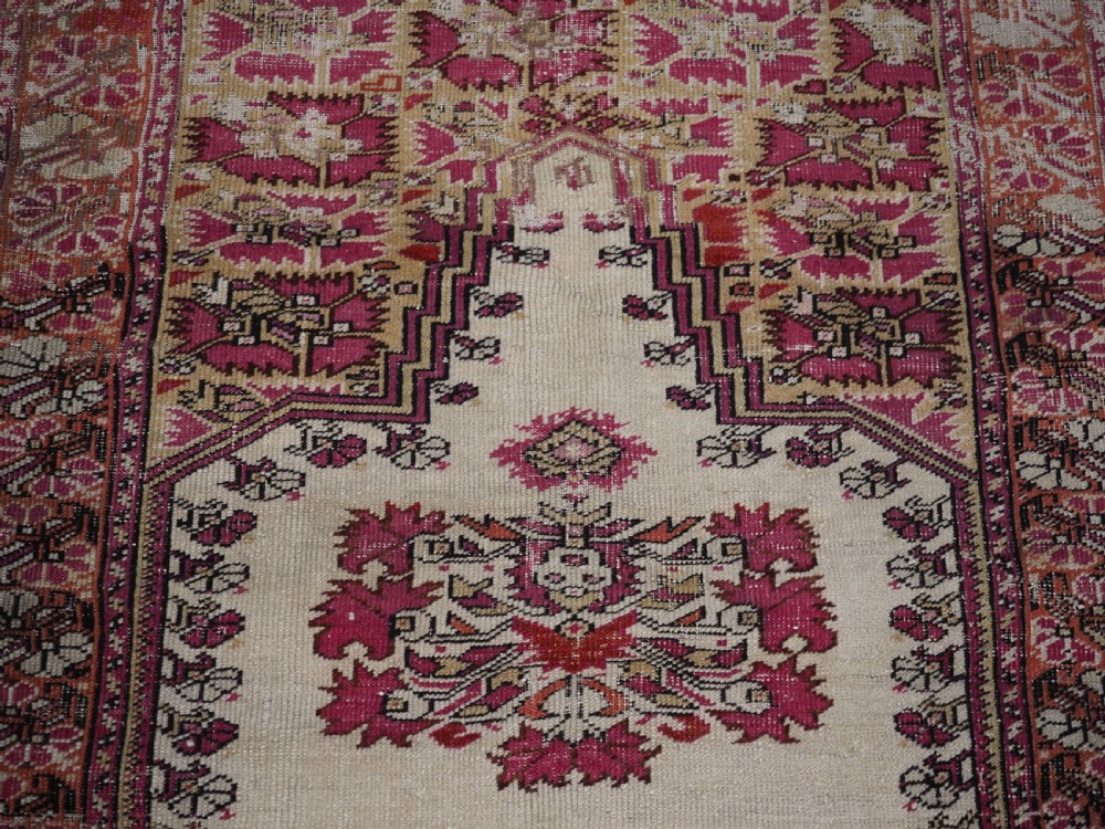 An antique Turkish Ghiordes prayer rug featuring a cream central niche framed by multi-banded red and burgundy patterned borders. View IX