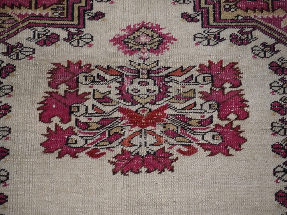 An antique Turkish Ghiordes prayer rug featuring a cream central niche framed by multi-banded red and burgundy patterned borders. View X