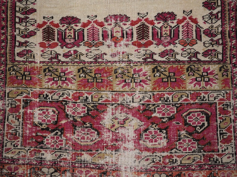 An antique Turkish Ghiordes prayer rug featuring a cream central niche framed by multi-banded red and burgundy patterned borders. View XI