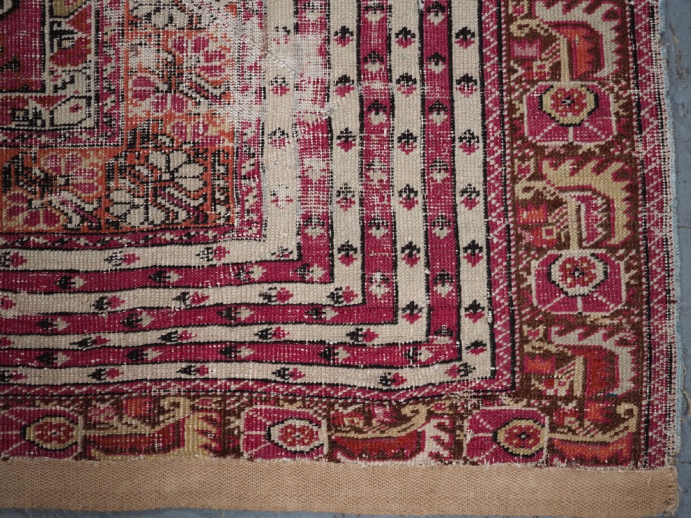 An antique Turkish Ghiordes prayer rug featuring a cream central niche framed by multi-banded red and burgundy patterned borders. View XII