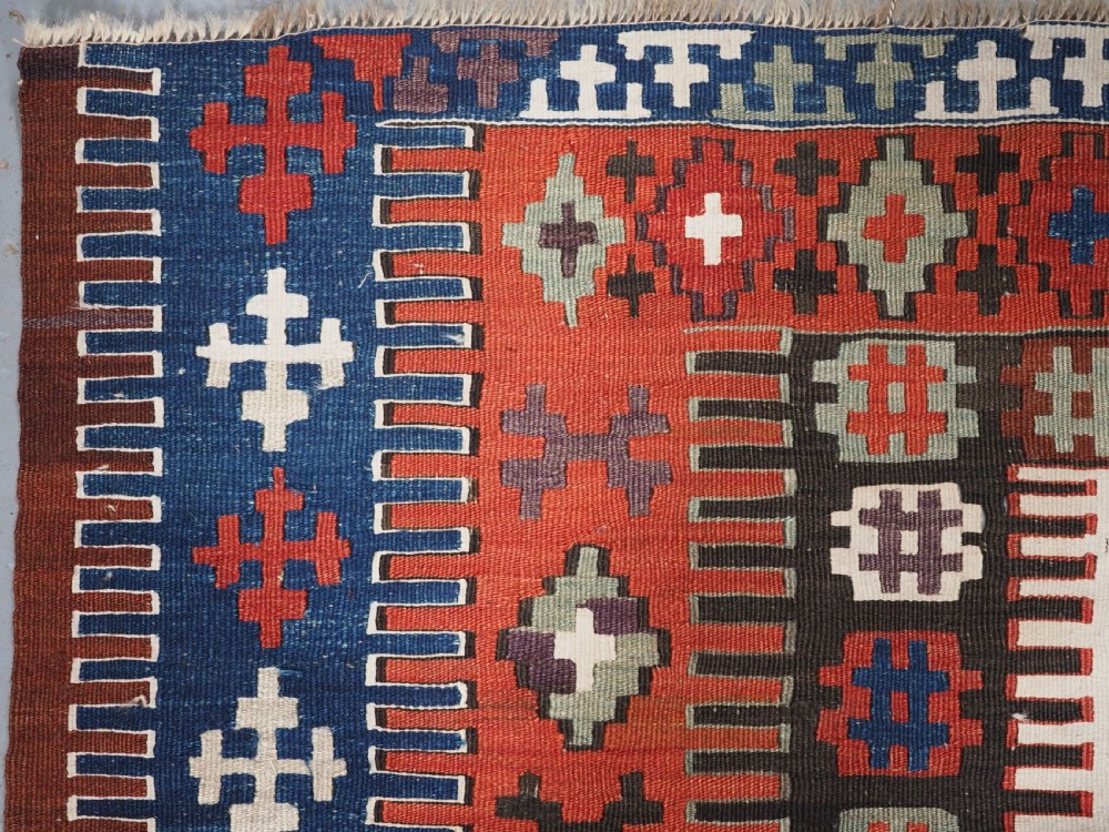 An antique handwoven Turkish Obruk kilim rug featuring a central mihrab niche motif surrounded by geometric borders in terracotta red, dark blue, green, and dark brown. View III
