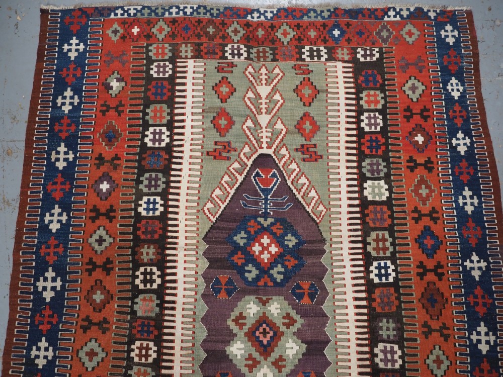 An antique handwoven Turkish Obruk kilim rug featuring a central mihrab niche motif surrounded by geometric borders in terracotta red, dark blue, green, and dark brown. View IV
