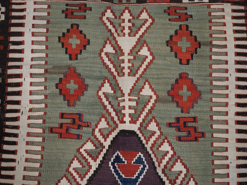 An antique handwoven Turkish Obruk kilim rug featuring a central mihrab niche motif surrounded by geometric borders in terracotta red, dark blue, green, and dark brown. View VIII