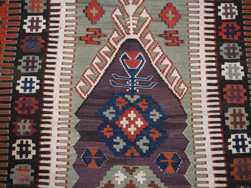 An antique handwoven Turkish Obruk kilim rug featuring a central mihrab niche motif surrounded by geometric borders in terracotta red, dark blue, green, and dark brown. View IX