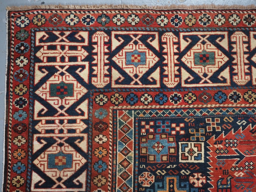 An antique late 19th-century Caucasian Shirvan hand-knotted wool rug featuring geometric diamond medallions, multi-coloured tribal motifs, and a distinct Kufic border. View VI