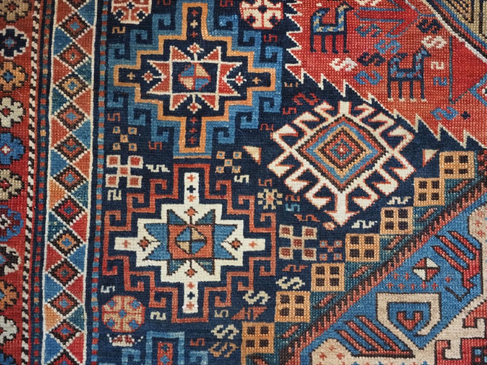 An antique late 19th-century Caucasian Shirvan hand-knotted wool rug featuring geometric diamond medallions, multi-coloured tribal motifs, and a distinct Kufic border. View IX