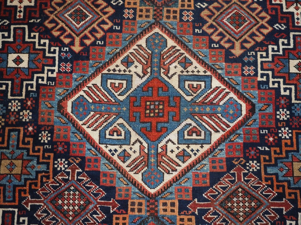 An antique late 19th-century Caucasian Shirvan hand-knotted wool rug featuring geometric diamond medallions, multi-coloured tribal motifs, and a distinct Kufic border. View XI
