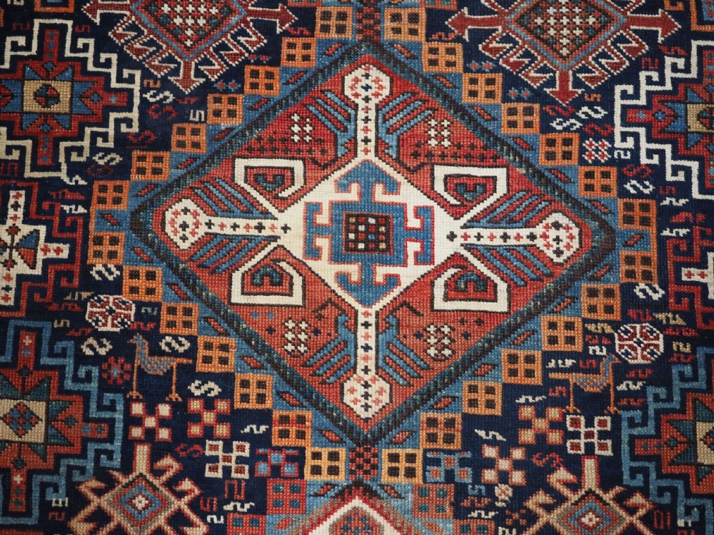 An antique late 19th-century Caucasian Shirvan hand-knotted wool rug featuring geometric diamond medallions, multi-coloured tribal motifs, and a distinct Kufic border. View XII