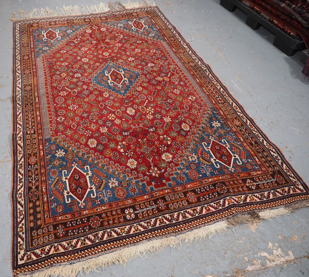 An antique hand-knotted wool Qashqai rug featuring a central stepped medallion surrounded by intricate geometric motifs in shades of terracotta red, indigo blue, and ivory. View II