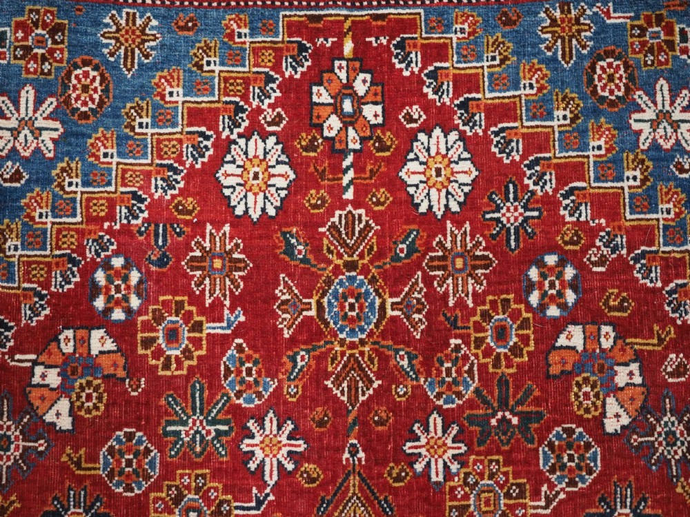 An antique hand-knotted wool Qashqai rug featuring a central stepped medallion surrounded by intricate geometric motifs in shades of terracotta red, indigo blue, and ivory. View IX