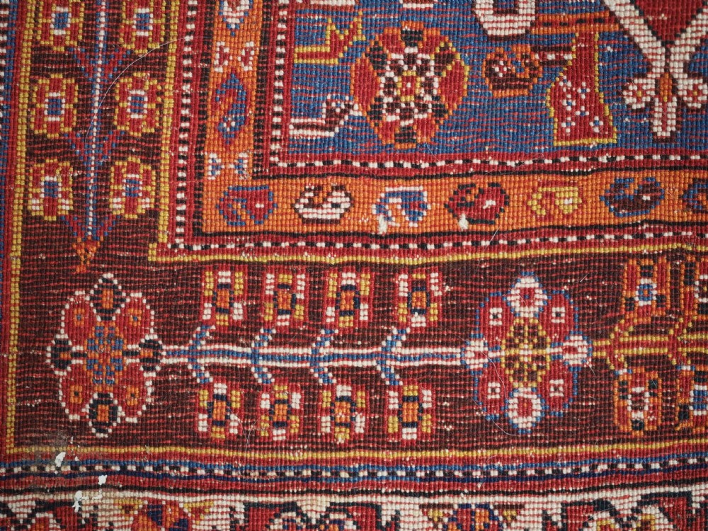 An antique hand-knotted wool Qashqai rug featuring a central stepped medallion surrounded by intricate geometric motifs in shades of terracotta red, indigo blue, and ivory. View XVI