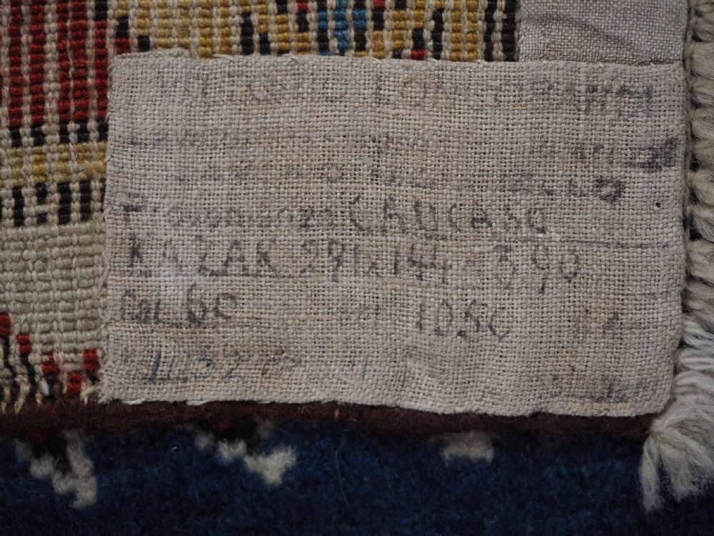 An antique hand-knotted Caucasian Kasim-Usag wool rug featuring geometric red and ivory medallions set on a dark navy blue field with multi-coloured geometric borders. View XVI