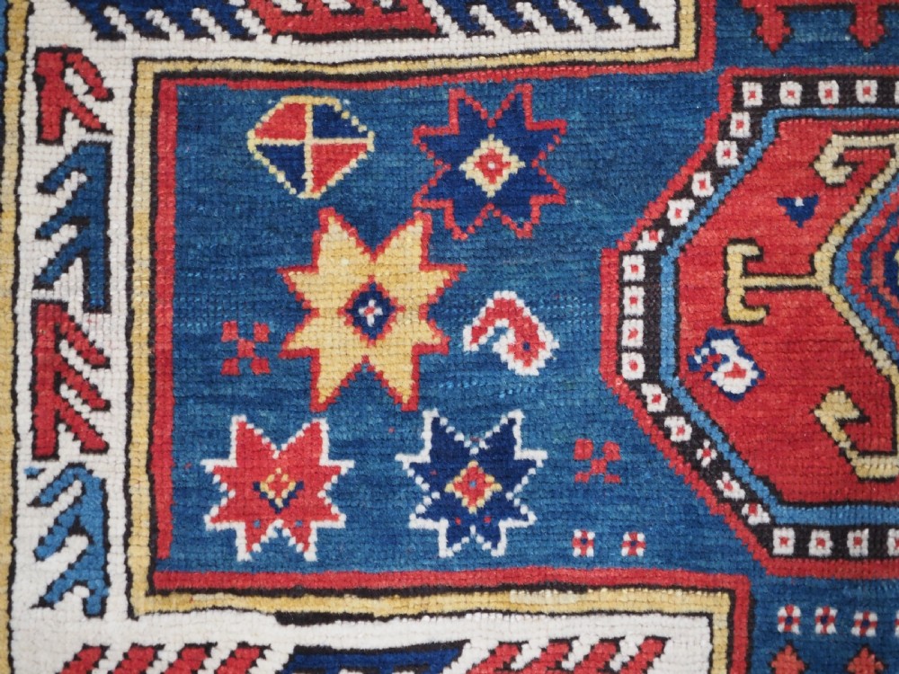 An antique Caucasian Sewan Kazak wool rug featuring a red keyhole medallion set against a navy blue and cream background with geometric borders. View XI
