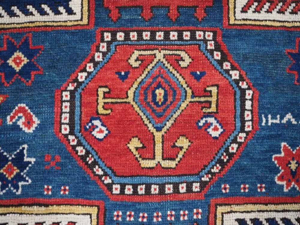 An antique Caucasian Sewan Kazak wool rug featuring a red keyhole medallion set against a navy blue and cream background with geometric borders. View XII
