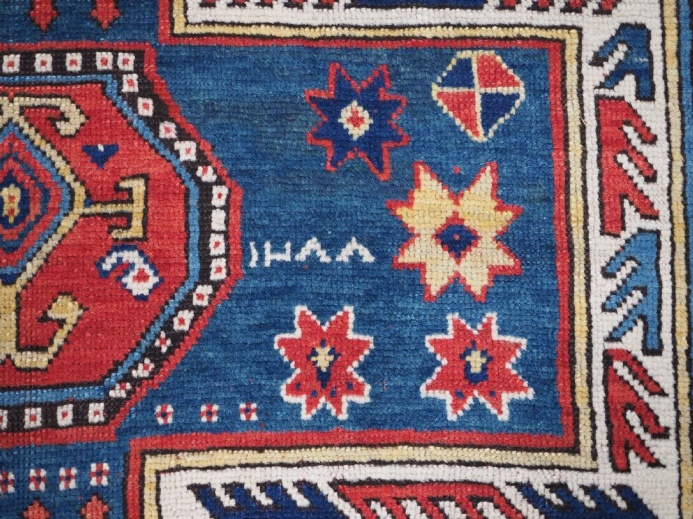 An antique Caucasian Sewan Kazak wool rug featuring a red keyhole medallion set against a navy blue and cream background with geometric borders. View XIII