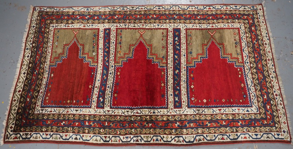 An antique Turkish Sivas Saf hand-knotted wool rug featuring three distinct red stepped prayer niches framed by olive green panels and multi-layered geometric borders.