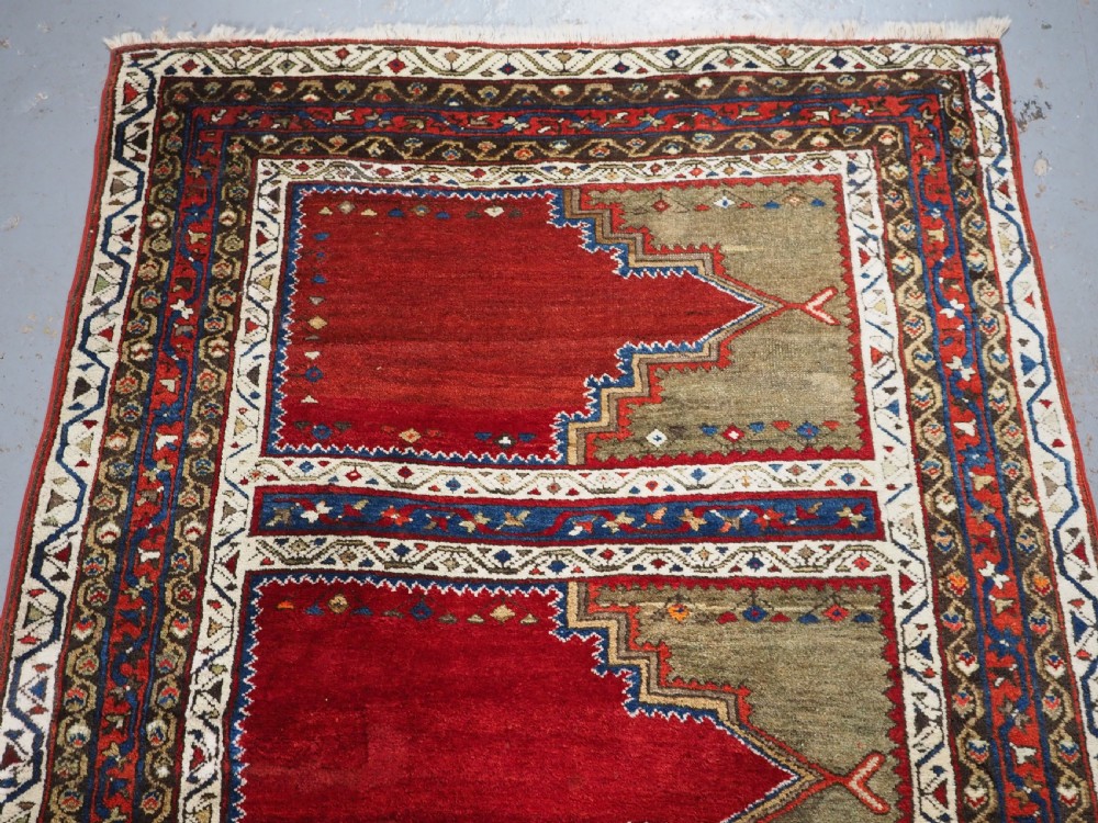An antique Turkish Sivas Saf hand-knotted wool rug featuring three distinct red stepped prayer niches framed by olive green panels and multi-layered geometric borders. View III