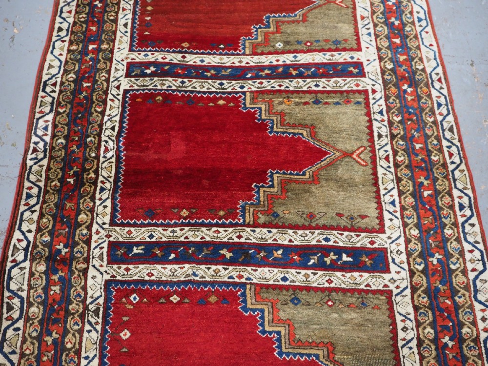 An antique Turkish Sivas Saf hand-knotted wool rug featuring three distinct red stepped prayer niches framed by olive green panels and multi-layered geometric borders. View IV