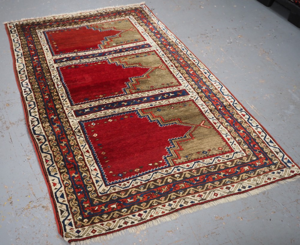 An antique Turkish Sivas Saf hand-knotted wool rug featuring three distinct red stepped prayer niches framed by olive green panels and multi-layered geometric borders. View IX