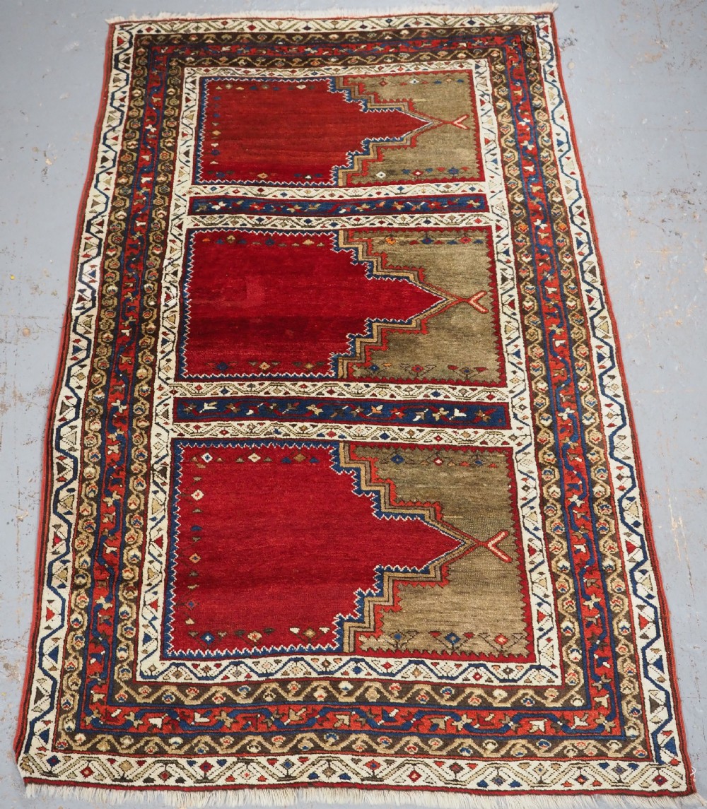 An antique Turkish Sivas Saf hand-knotted wool rug featuring three distinct red stepped prayer niches framed by olive green panels and multi-layered geometric borders. View X