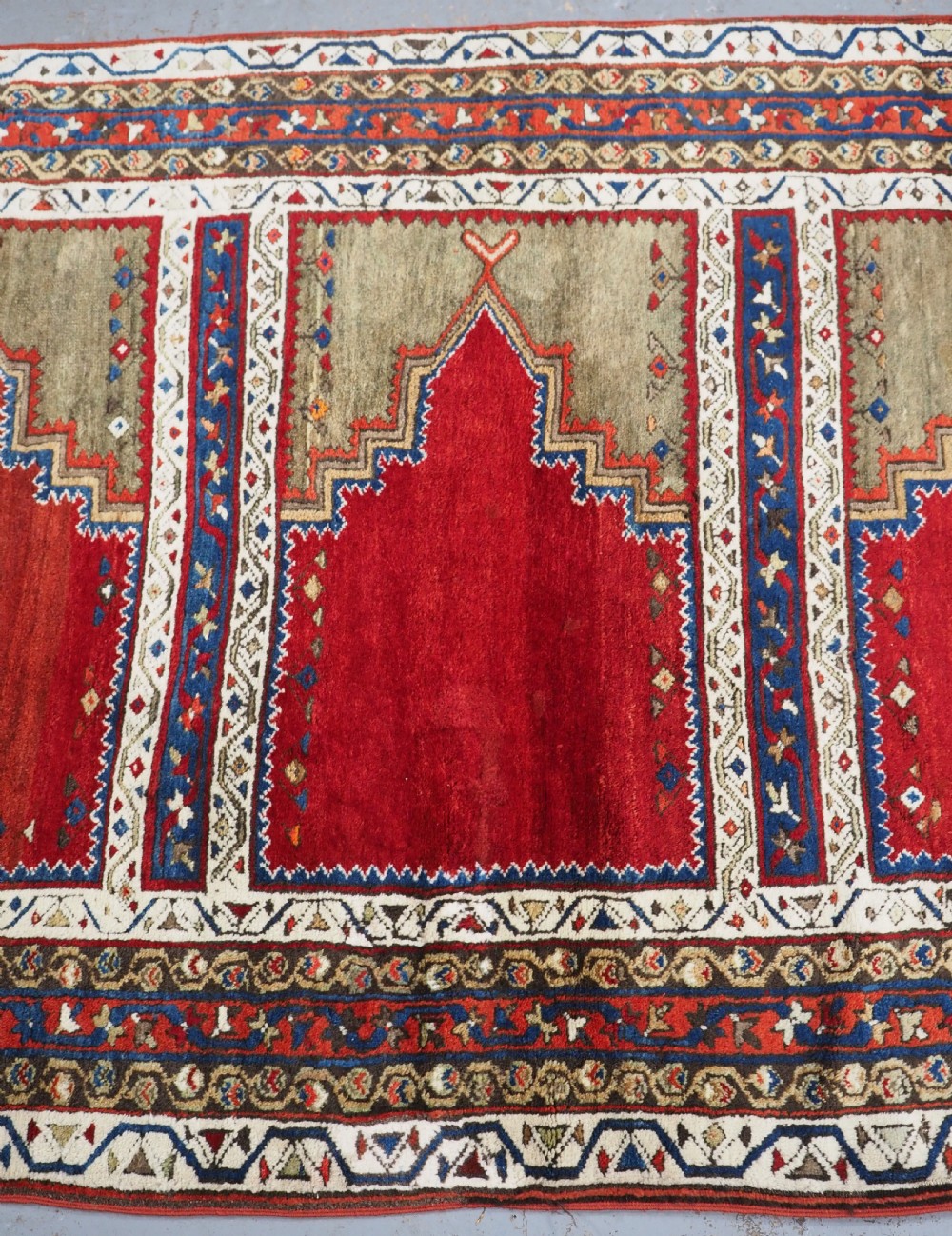 An antique Turkish Sivas Saf hand-knotted wool rug featuring three distinct red stepped prayer niches framed by olive green panels and multi-layered geometric borders. View XII