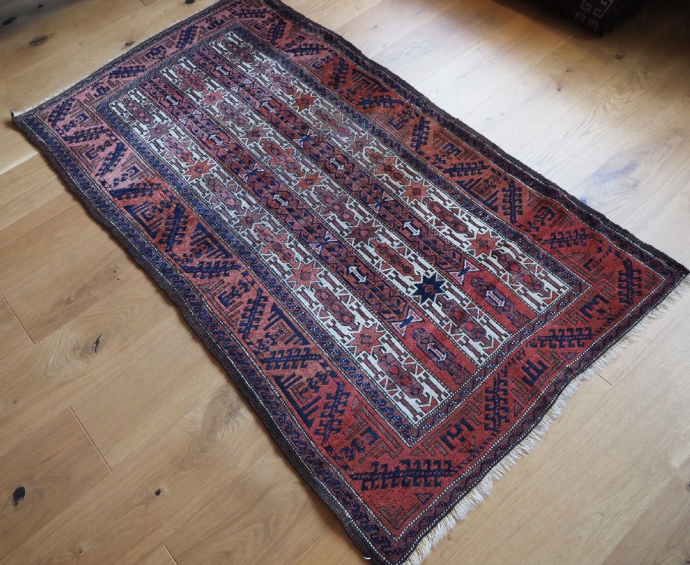 An antique hand-knotted Baluch wool rug featuring vertical stripe patterns in terracotta, navy blue, and white tones. View II