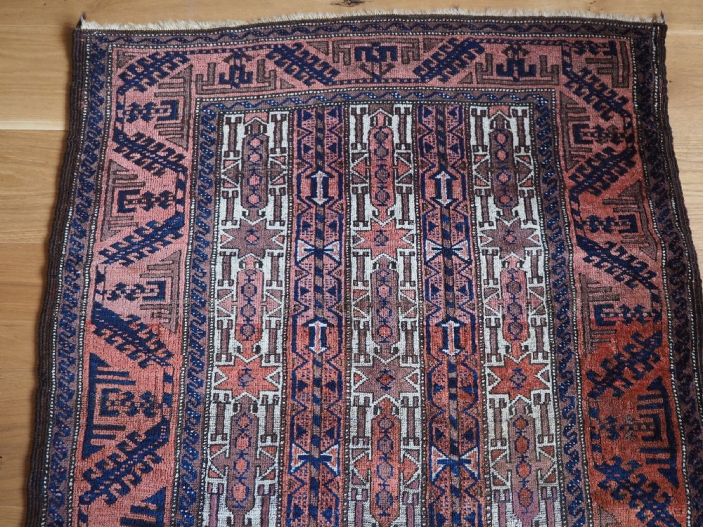 An antique hand-knotted Baluch wool rug featuring vertical stripe patterns in terracotta, navy blue, and white tones. View III