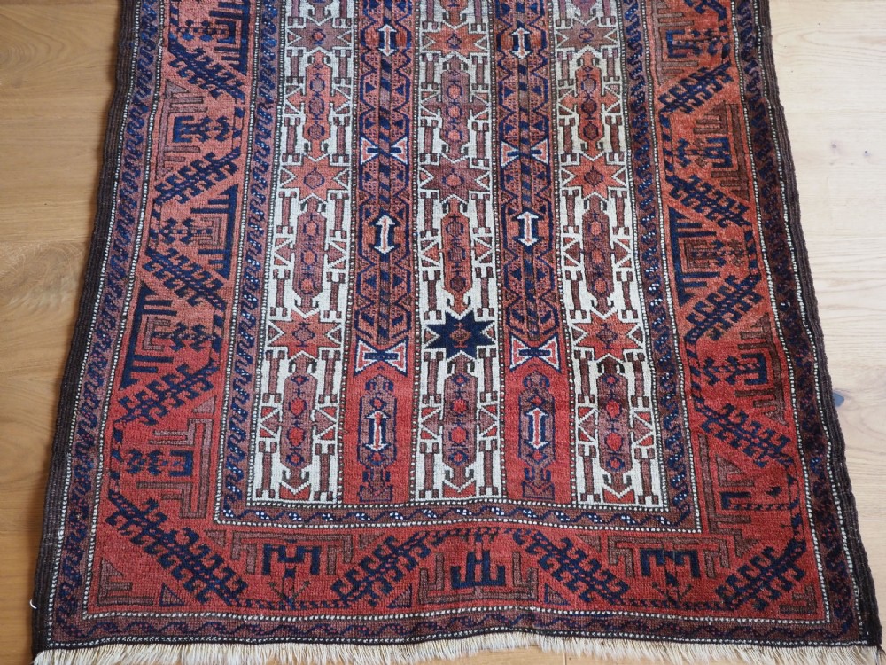 An antique hand-knotted Baluch wool rug featuring vertical stripe patterns in terracotta, navy blue, and white tones. View V