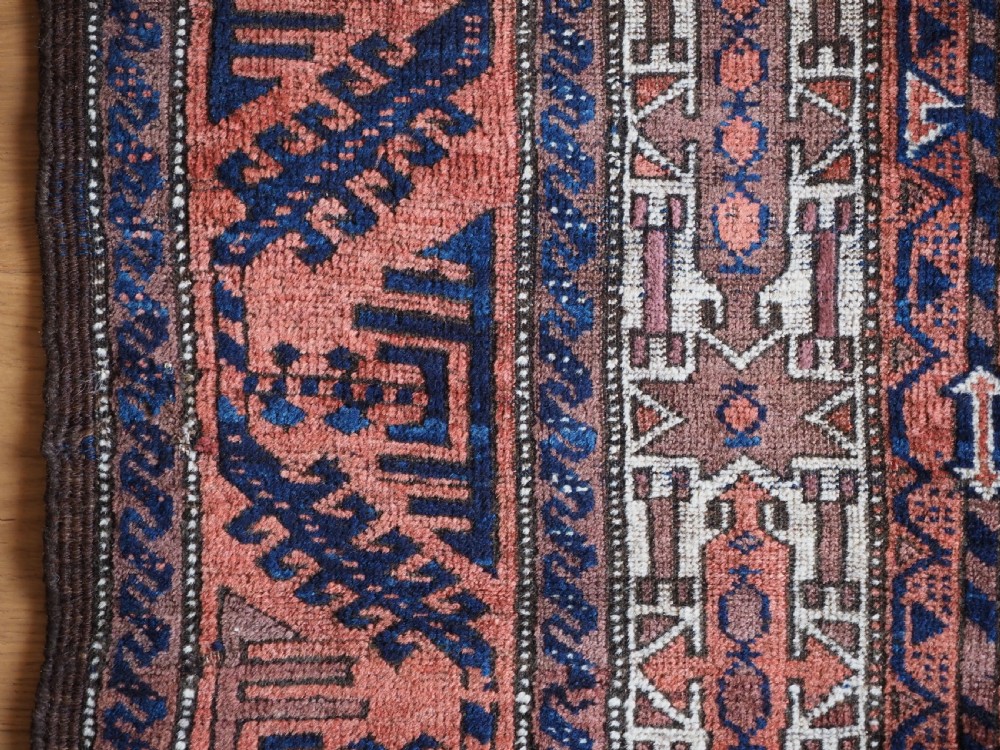 An antique hand-knotted Baluch wool rug featuring vertical stripe patterns in terracotta, navy blue, and white tones. View VII