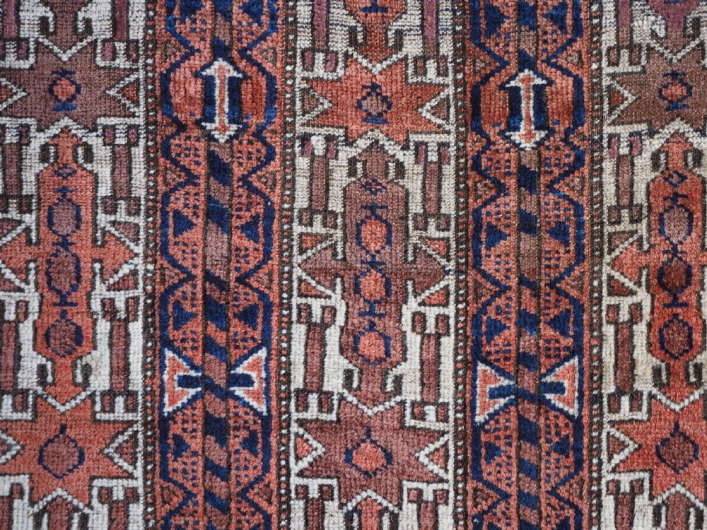 An antique hand-knotted Baluch wool rug featuring vertical stripe patterns in terracotta, navy blue, and white tones. View IX