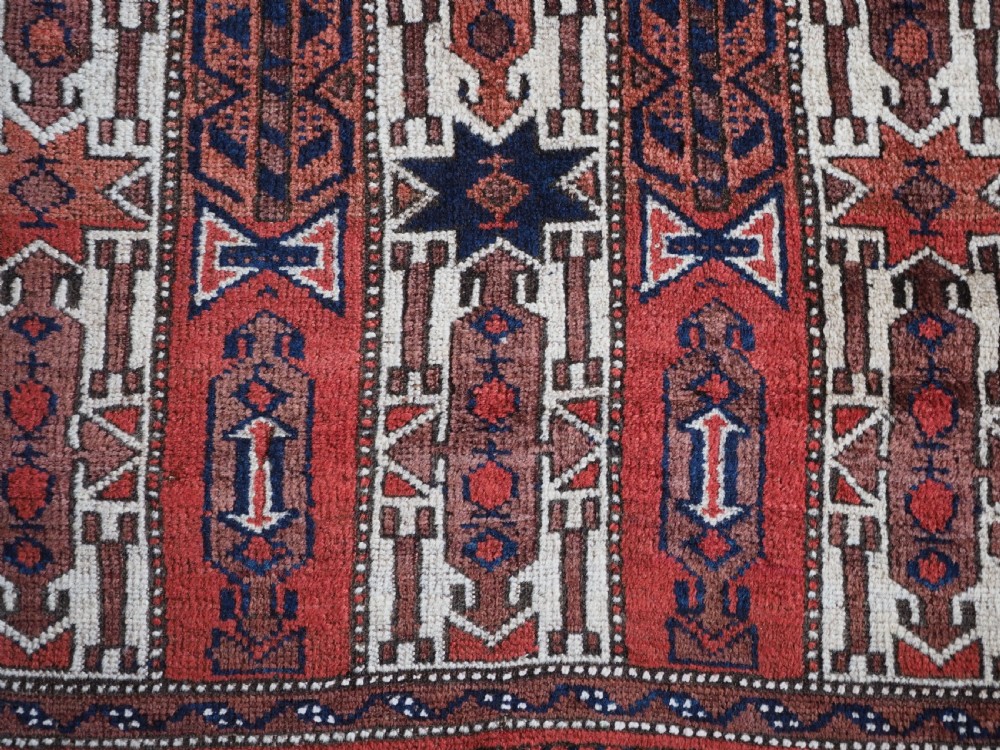 An antique hand-knotted Baluch wool rug featuring vertical stripe patterns in terracotta, navy blue, and white tones. View X