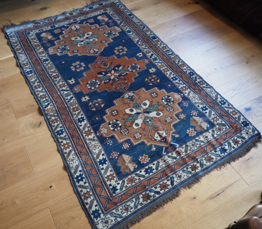 An antique Caucasian Derbent hand-knotted wool rug featuring three stepped medallions on a deep blue field with geometric borders. View II