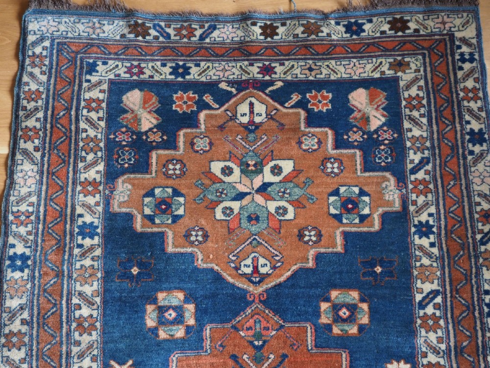 An antique Caucasian Derbent hand-knotted wool rug featuring three stepped medallions on a deep blue field with geometric borders. View III